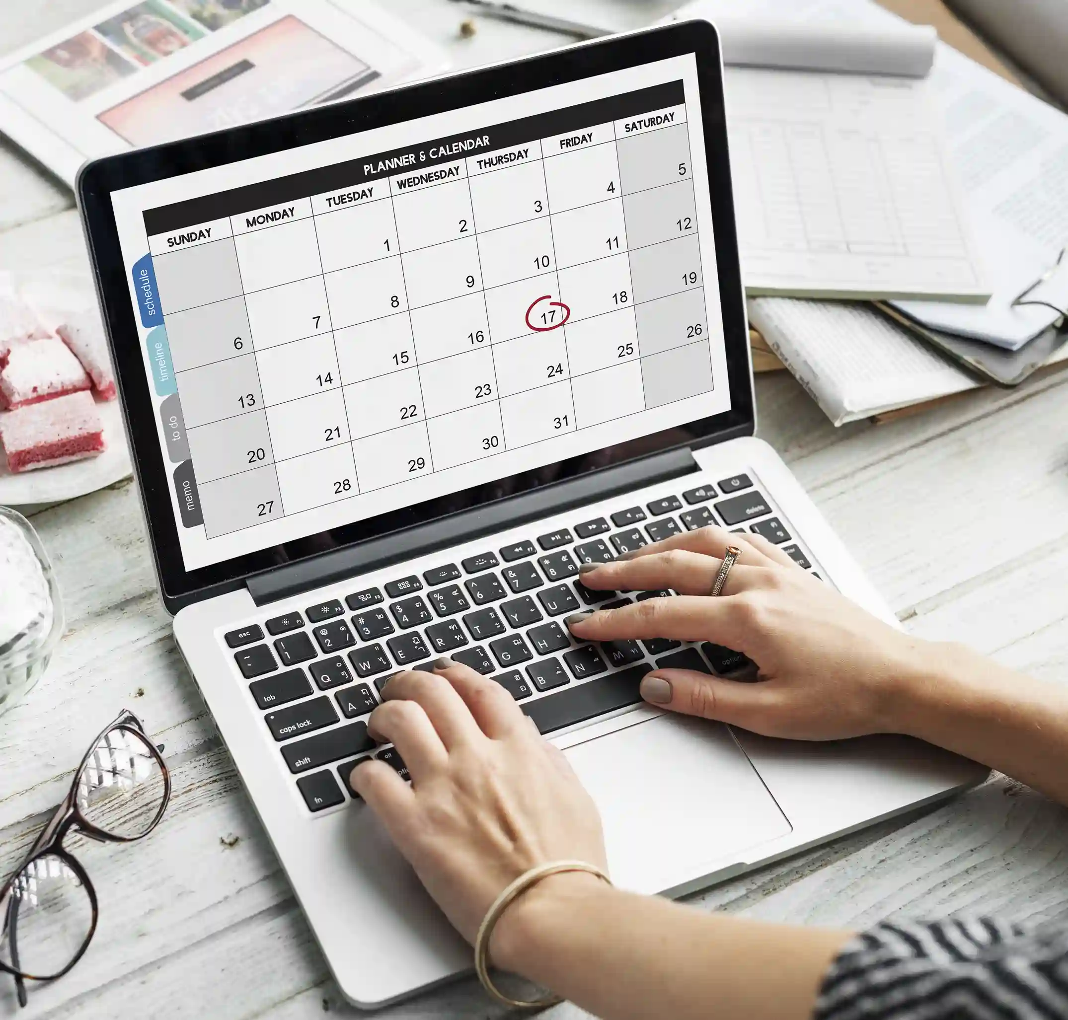 Hands typing on a laptop showing a monthly planner calendar with an appointment date circled